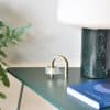 Sleek tape dispenser on a modern dark green desk next to a minimalist white lamp and a blue book, showcasing stylish home office organization and contemporary decor.