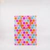 Colorful polka dot gift bag with orange rope handles, vibrant design perfect for special occasions, parties, and celebrations. Stylish packaging from The Wraperie for memorable gift-giving.
