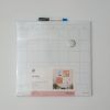 Dry erase calendar on wall, magnetic surface for scheduling and planning, ideal for home or office organization, from The Wraperie collection.
