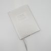 A clear feeding journal notebook with lined pages and a ribbon bookmark, designed for tracking baby's feeding schedule, perfect for new parents and caregivers.
