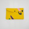 Bright yellow colorful clutch wallet with abstract purple, green, black, and pink accents, perfect for fashion-forward accessories and casual outings.