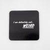 Wide black coaster with humorous white text "I am definitely not... WEIRD" for snack bars and catering. Perfect for food presentation, party decoration, and cafe displays. Durable, stylish, and conversation-starting.