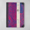 Vibrant marbled notebook with colorful swirling patterns in red, blue, and purple, featuring black spine and white label with logo and website for The Wraperie.