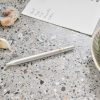 Fresh garlic cloves and a handwritten recipe note on a speckled countertop, with an artichoke in a decorative bowl, highlighting the fresh ingredients and culinary focus of The Wraperie.