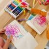 Colorful children drawing with markers on white paper, showcasing creative art activities for kids at The Wraperie.