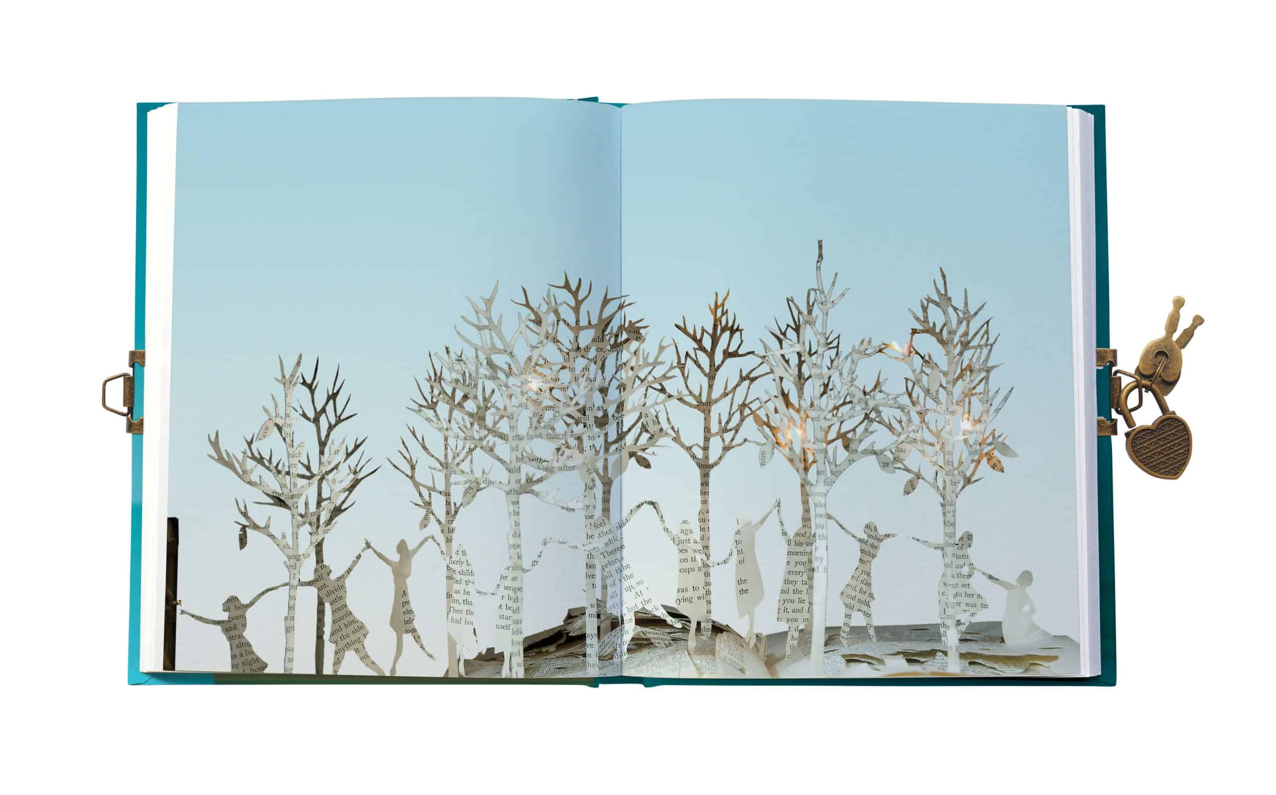 Intricate paper-cut art of trees and children, highlighting craft and artistic expression, displayed within a book, representing creativity and artistry.