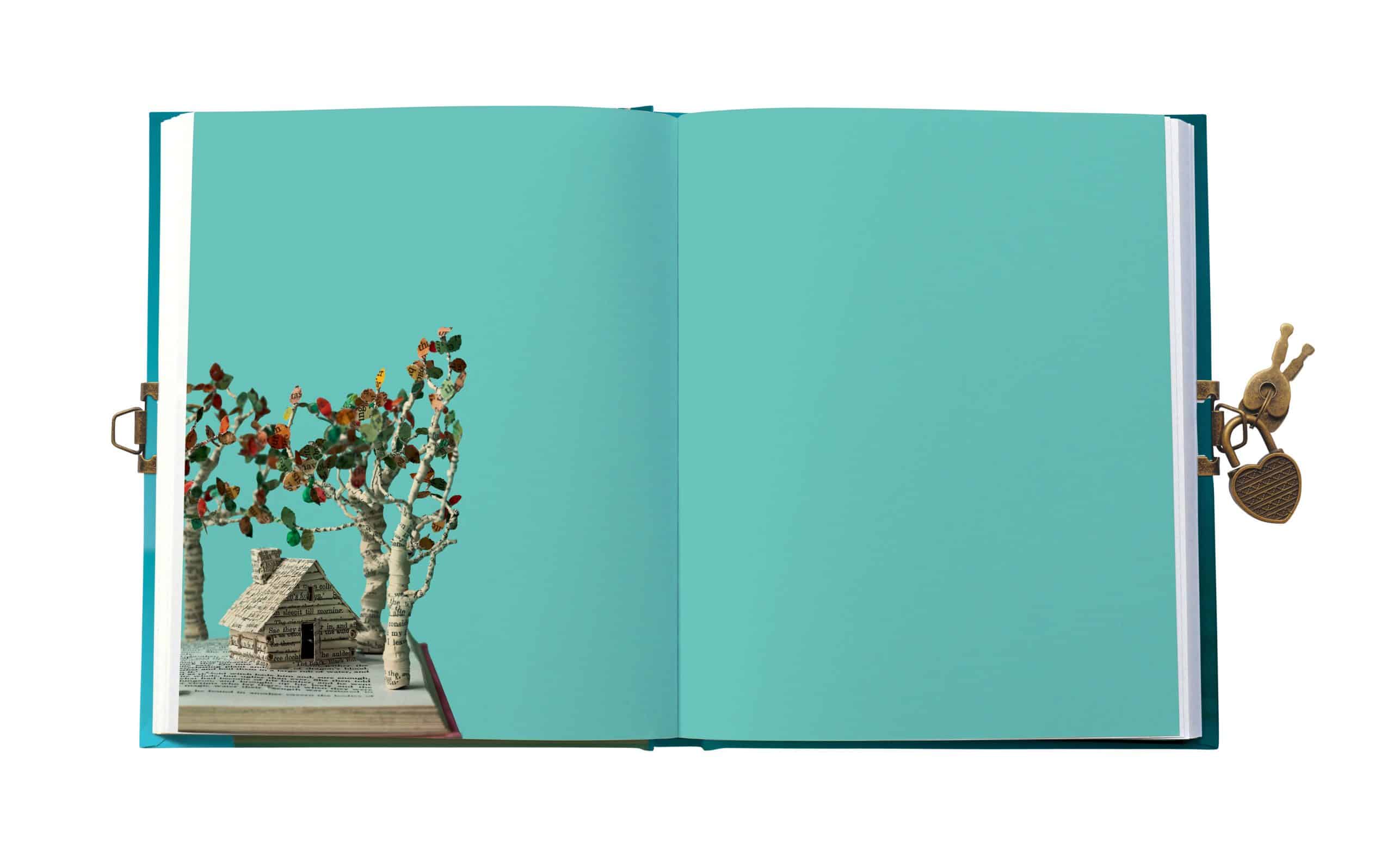 Colorful book art with miniature houses and tree-shaped paper crafts on open pages, featuring whimsical metal lock and key on the right side, illustrating creative gift wrapping by The Wraperie.