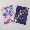 Vibrant floral watercolor notebook with pink, purple, and blue blooms; elegant navy notebook with gold “Adventures” lettering for journaling and note-taking.
