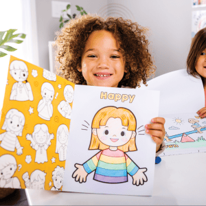 Coloring pages for kids, happy girl holding vibrant "Happy" themed coloring sheet, creative activity at The Wraperie children's art studio, engaging educational fun for children.