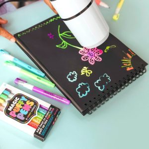 Brightly colored chalk markers and a spiral notebook with colorful chalk drawings of flowers and clouds on a pastel background.