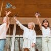 Colorful paper airplanes flying in the air as kids enjoy a fun party at The Wraperie, creating joyful memories with friends in a cozy indoor setting.