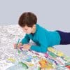 Coloring activity by a young boy on a large, detailed coloring poster with various cityscapes and landmarks, promoting creativity and entertainment at The Wraperie.