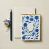 Blue floral birthday greeting card with gold scalloped edges on a neutral background.