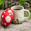 Colorful mushroom-shaped ceramic coffee mug with floral design, outdoor setting, perfect for cozy mornings, garden tea moments, whimsical kitchen decor, Nature-inspired coffee cup, The Wraperie.