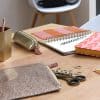 Brightly colored planner notebooks, gold pencil case, decorative scissors, and stationery supplies on a wooden desk for organization and creative work at The Wraperie.