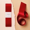 Red satin ribbon with torn packaging and a gift tag, perfect for gift wrapping and special occasions.