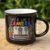 Colorful camera-themed coffee mug with floral decorations, featuring the quote 