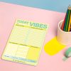 Vibes daily planner with sections for to-do lists, gratitude, and positive affirmations on a pastel pink and blue background with colorful pens and decorative tape.