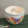 Colorful ceramic candle holder with butterfly design and the inscription 