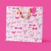 Pink gift bag with bow patterns for The Wraperie, perfect for special occasions and gift wrapping. Made with high-quality material, featuring pink, peach, and cream bows on a pastel background.