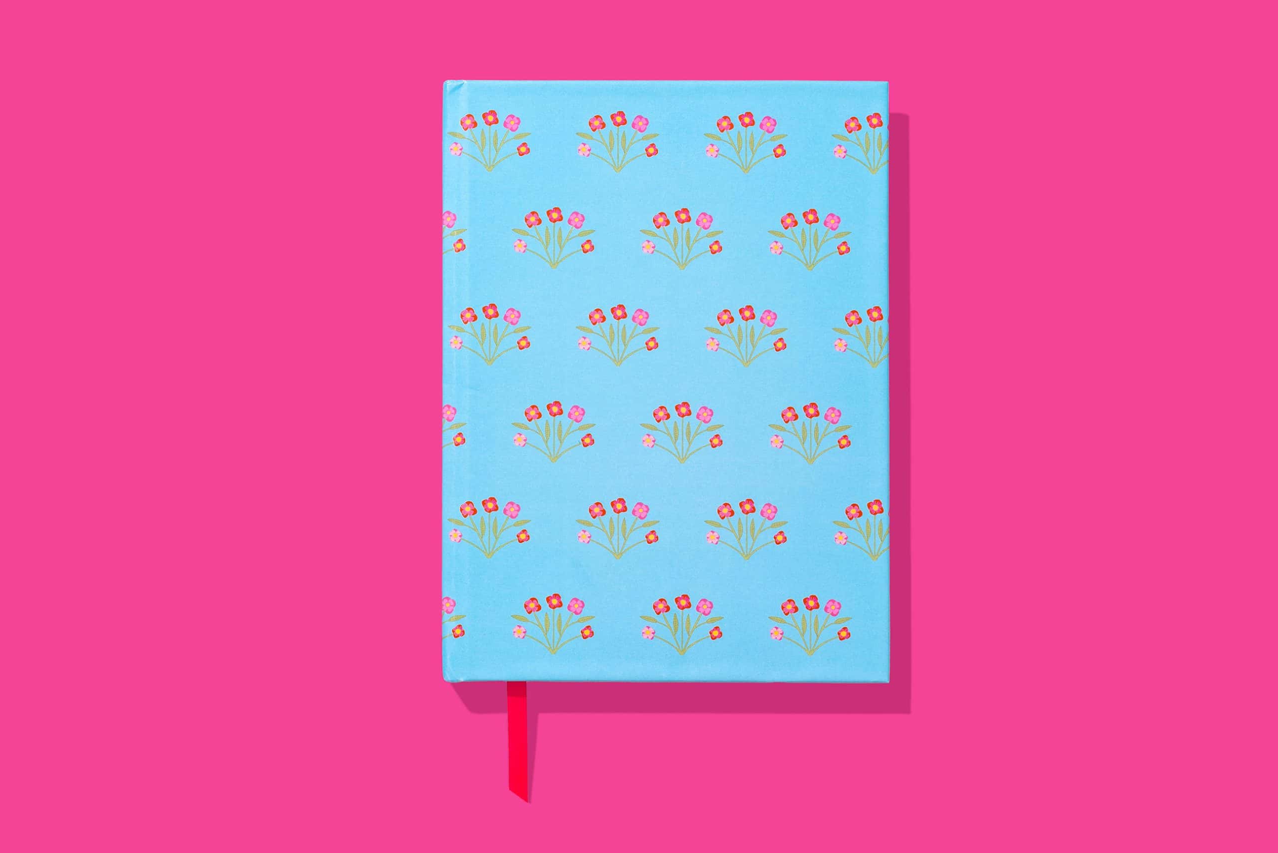 Vibrant blue planner with pink and red flower pattern, set against a pink background, perfect for organizing and style.