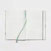A lined open notebook with a mint green ribbon bookmark, ideal for journaling or note-taking.