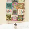 Colorful motivational quote stickers on a spiral-bound notebook cover, featuring positive affirmations and vibrant floral designs, perfect for inspiring mental health and self-care.