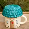 Colorful ceramic house mug with a textured blue roof, whimsical floral design, and a cozy door and windows, perfect for charming home decor or a cute coffee cup.