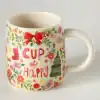 Colorful holiday-themed ceramic mug featuring festive words 