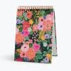 Vibrant floral patterned desk calendar with gold spiral binding, perfect for stylish home or office decor. Bright, colorful flower design enhances productivity and adds a cheerful touch.