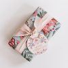 Festive gift wrapped with holiday-themed floral paper, pale pink satin ribbon, and a