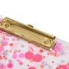 Shiny gold stapler with pink and purple confetti, glitter, and snowflake-shaped embellishments on a white background. Perfect for craft projects and gift wrapping.