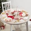 Festive Christmas table set with holiday-themed party supplies, gingerbread cookies, and decorations next to a decorated Christmas tree.