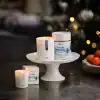 Aery Nordic Fireside candles displayed on a white cake stand with a festive background.