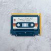 Vintage cassette tape with "Happy Birthday You Rock" handwritten note, on textured grey background, celebrating birthday with a retro music theme.