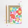 Colorful floral thank you card with cute, smiling faces on each flower, perfect for gifts or thank you notes from The Wraperie. Bright, cheerful design in pink, yellow, blue, and green.