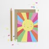 Vibrant colorful sun illustration greeting card with a smiling face, surrounded by rainbow rays on white background, perfect for cheerful occasions and creative designs.