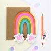 Colorful rainbow and cloud paper craft with pink smiley faces, perfect for kids' arts and crafts projects, available at The Wraperie.