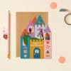 Colorful birthday card featuring a whimsical castle design with dragons, knights, and festive elements, perfect for celebrating special occasions.