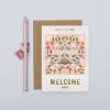 Colorful baby welcome card with nature-inspired illustration of birds, flowers, and mushrooms, perfect for celebrating new births at The Wraperie.