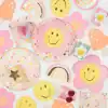 Pink flower-shaped paper plate with a yellow smiley face at The Wraperie, colorful party decor with rainbows, hearts, stars, and cute daisy-themed accents, perfect for cheerful celebrations.