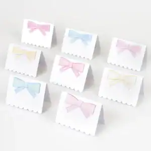 Pastel pink, blue, and yellow gift tags with bows on white scalloped background for event decor or gift wrapping.