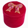 Shiny pink beaded bow brooch on red velvet jewelry box, perfect for elegant accessories and gift-giving.