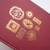 Gold foil wrapped designs on a maroon packaging box from The Wraperie, showcasing elegant, intricate patterns perfect for gift wrapping, showcasing high-quality craftsmanship and premium wrapping paper.