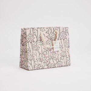 Delicate pink floral printed gift bag with cream ribbon handles, perfect for gift wrapping and presentation.