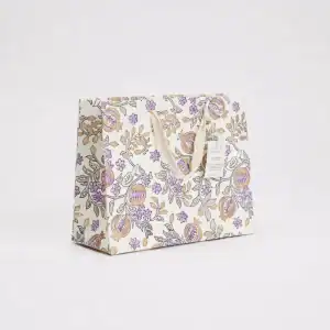 Colorful floral gift bag with elegant purple and gold accents, perfect for special occasions, crafted from high-quality paper, with sturdy cream-colored handles.