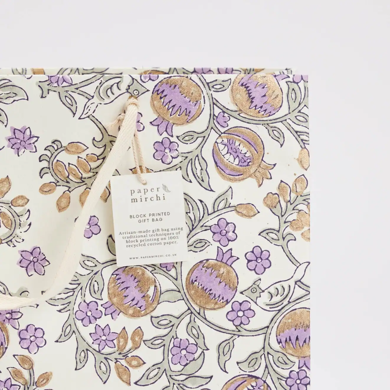 Vibrant floral print gift bag with purple and gold accents, perfect for special occasions, made from recycled cotton paper, showcasing eco-friendly craftsmanship by Paper Mirchi.