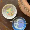 Colorful decorative bowls with moon and sun faces, perfect for playful tableware, on a wooden surface. Bright, whimsical design ideal for home decor or children’s accessories available at The Wraperie.
