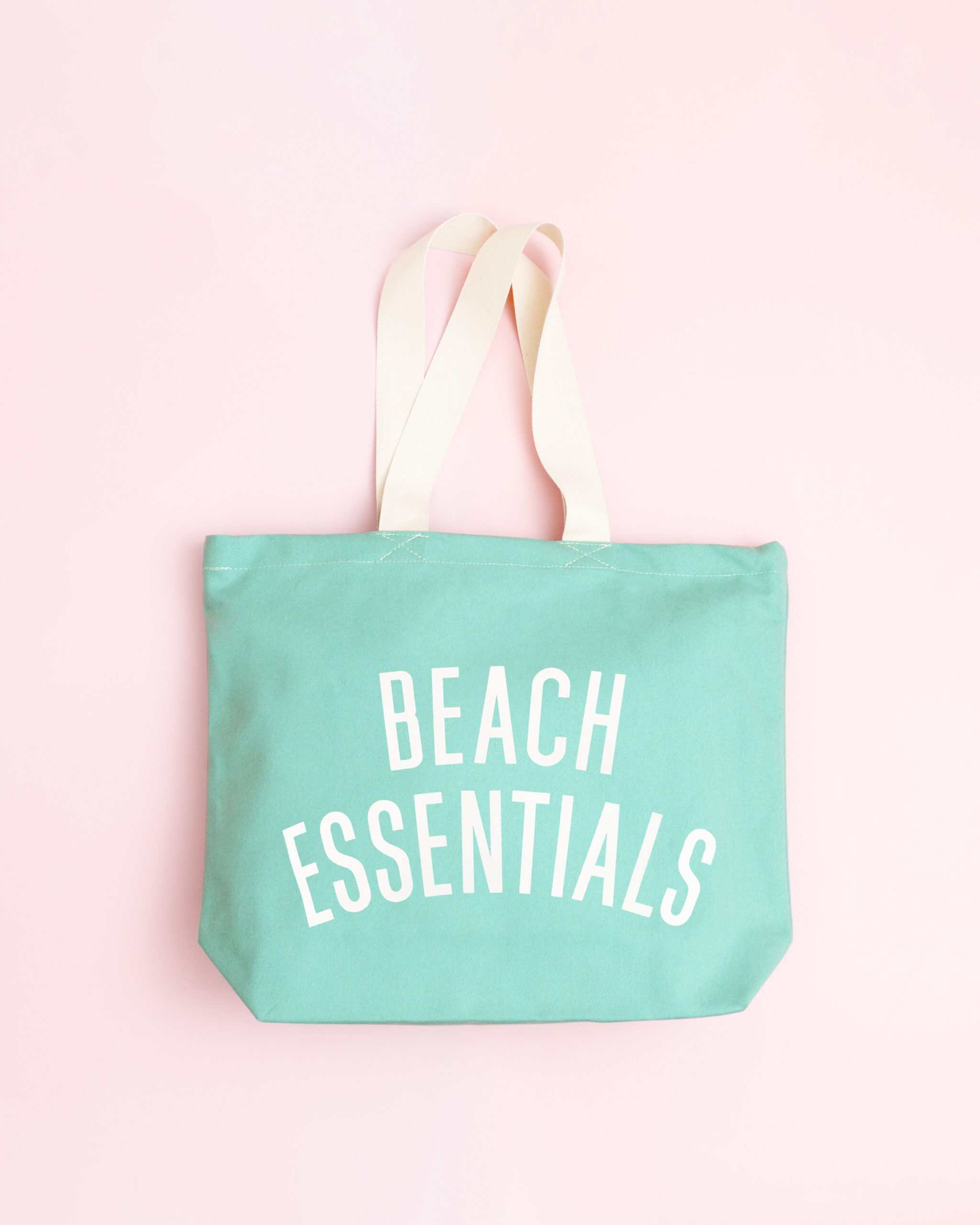 Bright teal tote bag with "Beach Essentials" text, perfect for summer trips and beach days.