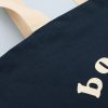 Black eco-friendly tote bag with beige handles, featuring the The Wraperie logo, perfect for sustainable shopping and food packaging needs.